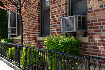 An air conditioning unit sticking out of the exterior wall of a brick home
